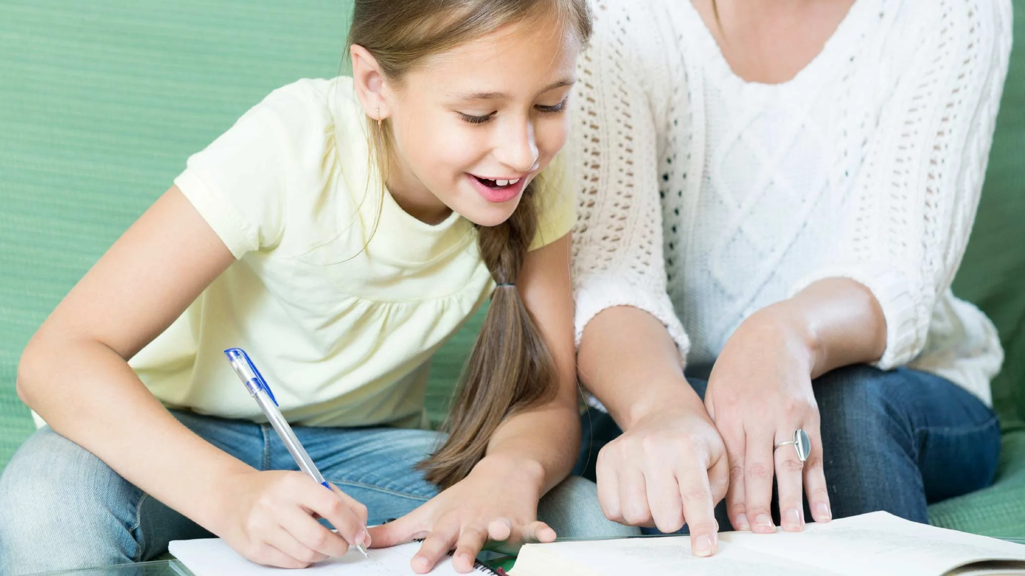 A volunteer helping a smiling child with schoolwork