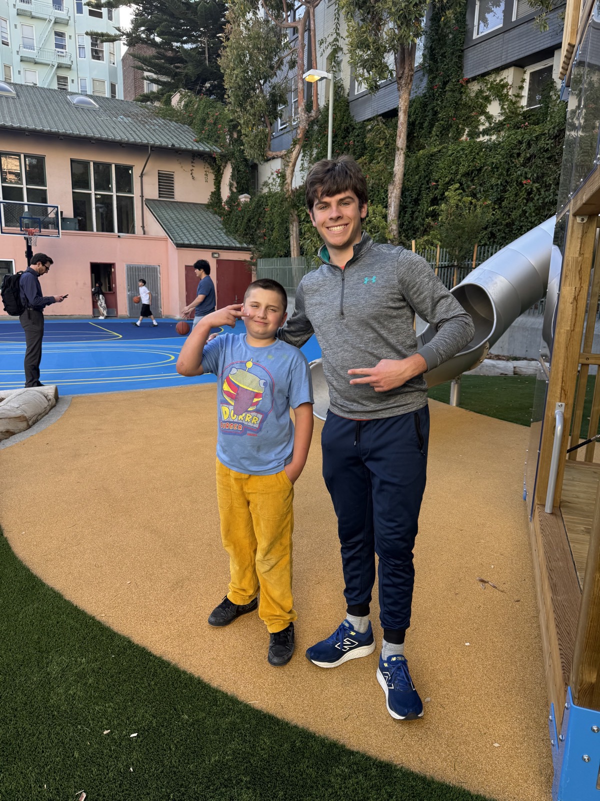 A volunteer and a child standing together on the playground after a session