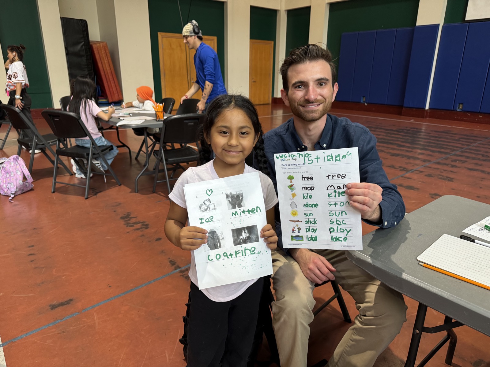 A volunteer and a child holding up the drawings and word lists they made together
