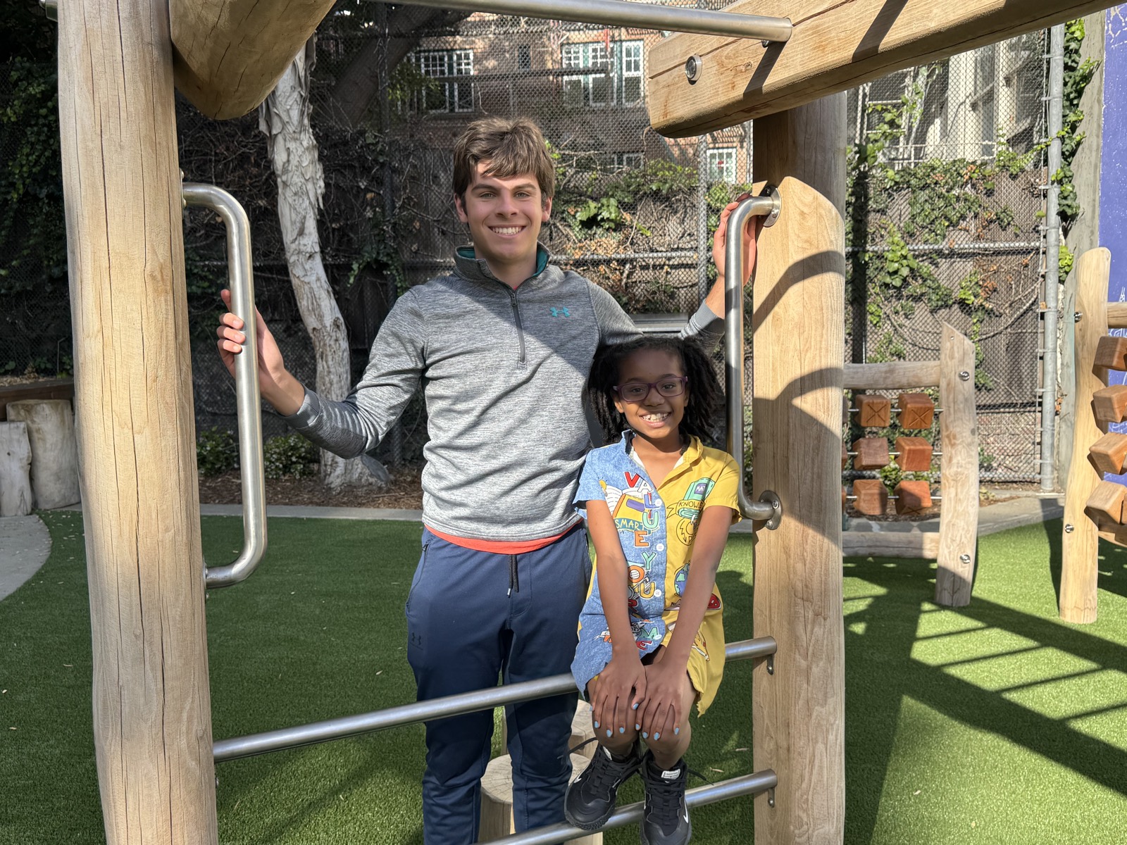 A volunteer and a child on the playground climbing frame