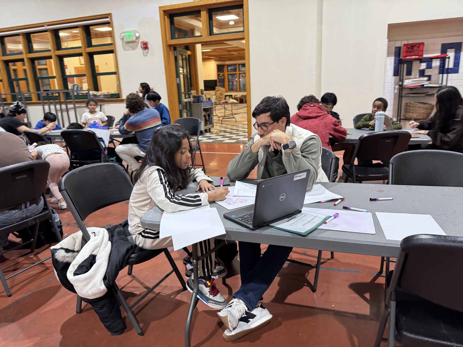 A volunteer and a child working through an assignment on a laptop